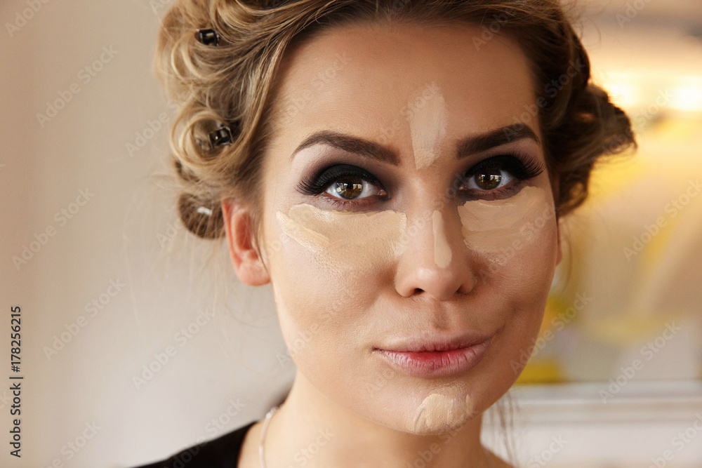 Fototapeta premium Pretty woman with dark smokey eyes makeup and highlighter under eyes and on the nose
