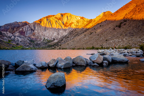 Mountain and rocks in lake at dawn photo