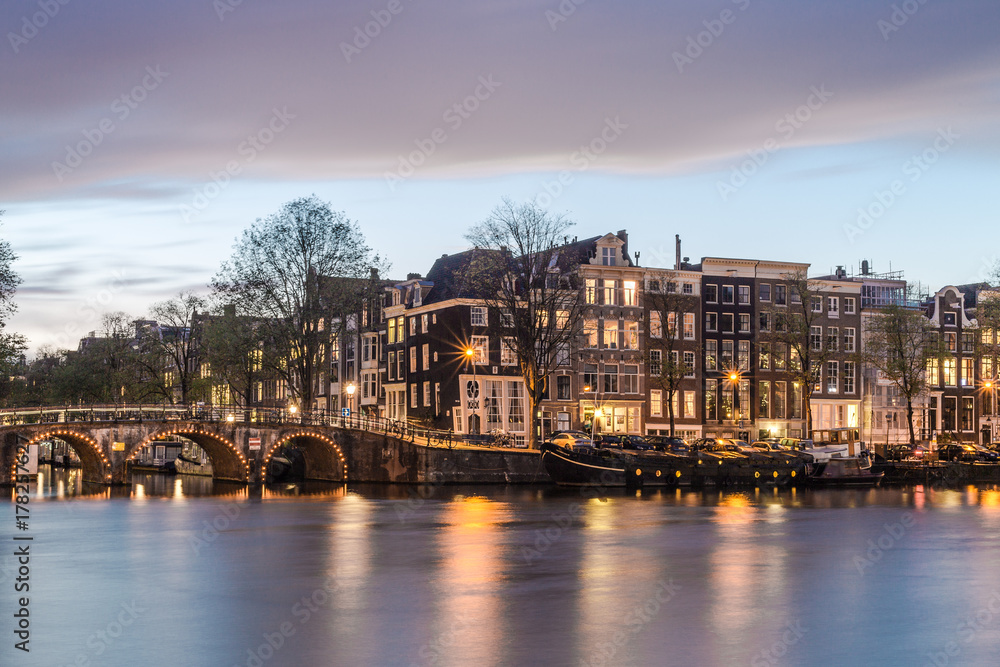 Old historic dutch houses, a bridge, canal, and boats in the evening at the twilight blue hour, Netherlands
