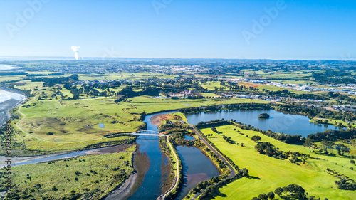 Aerial view on a beautiful bridge across a small stream with residential suburb on the background. New Zealand