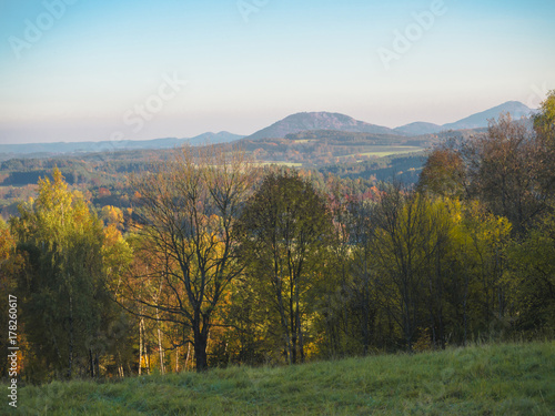 green meadow with autumn colorful forest and trees and hills before sunset landscape in luzicke hory mountain