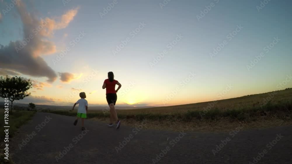 Running at sunset. Young woman with her son exercising in summer afternoon. Slow motion. Running at sunset. Young woman with her son exercising in summer afternoon. Slow motion.