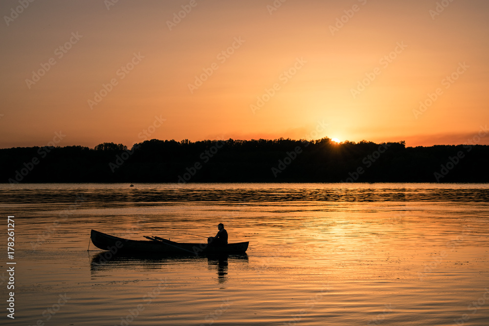 Fisherman with a both in the river on sunset