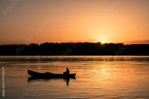 Fisherman with a both in the river on sunset