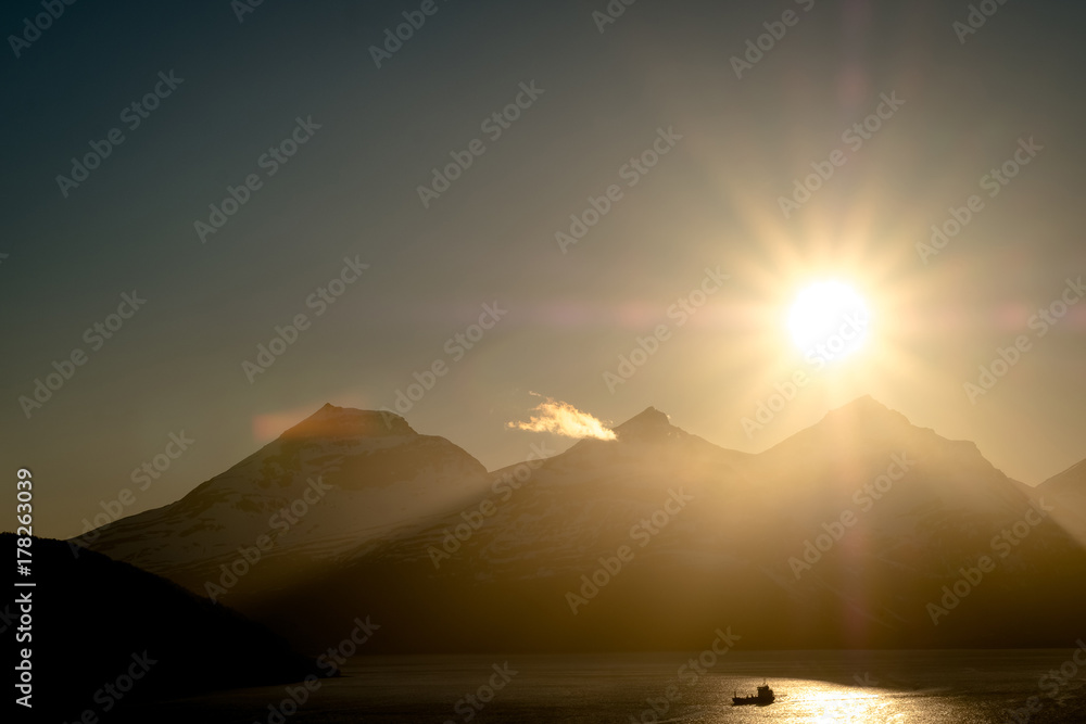 Fototapeta premium Scenic view of sunset over boat fishing in a dramatic landscape in Norway.