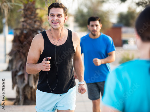 Smiling sportsmen are joggning race in time warm-up