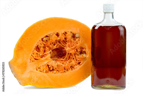 Pumpkin oil in a bottle and cut pumpkin isolated on a white background. photo