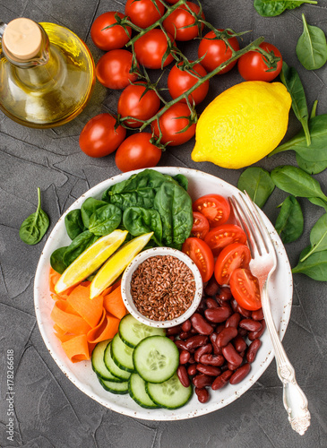 Vegetarian buddha bowl. Raw vegetables - tomatoes, cucumbers, beans, spinach, carrots, lemon and flax seed in a bowl. healthy, detox food concept. Selective focus