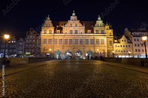 View of a cobblestone street and historic Green Gate, the formal residence of Poland's monarchs, at the Main Town in Gdansk, Poland, in the evening.