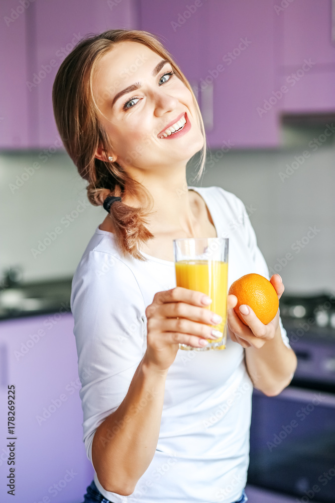 Cheerful young woman with orange juice and orange. The concept is healthy food, diet Cheerful young woman with orange juice and orange. The concept is healthy food, diet