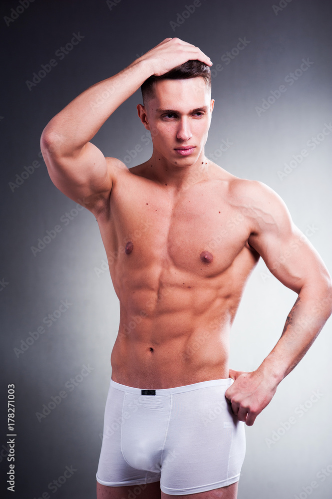 Fototapeta premium Young male athlete on a gray background