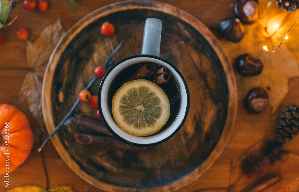 Fototapeta premium Glass of hot steaming tea and autumn plants on wooden table .