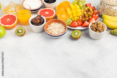 Top view of healthy breakfast with oats, variety of fruits, strawberries, mango, grapes, served on the white table, selective focus
