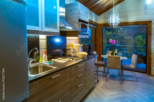 Kitchen in the country house. Living room with large windows. Wooden house.