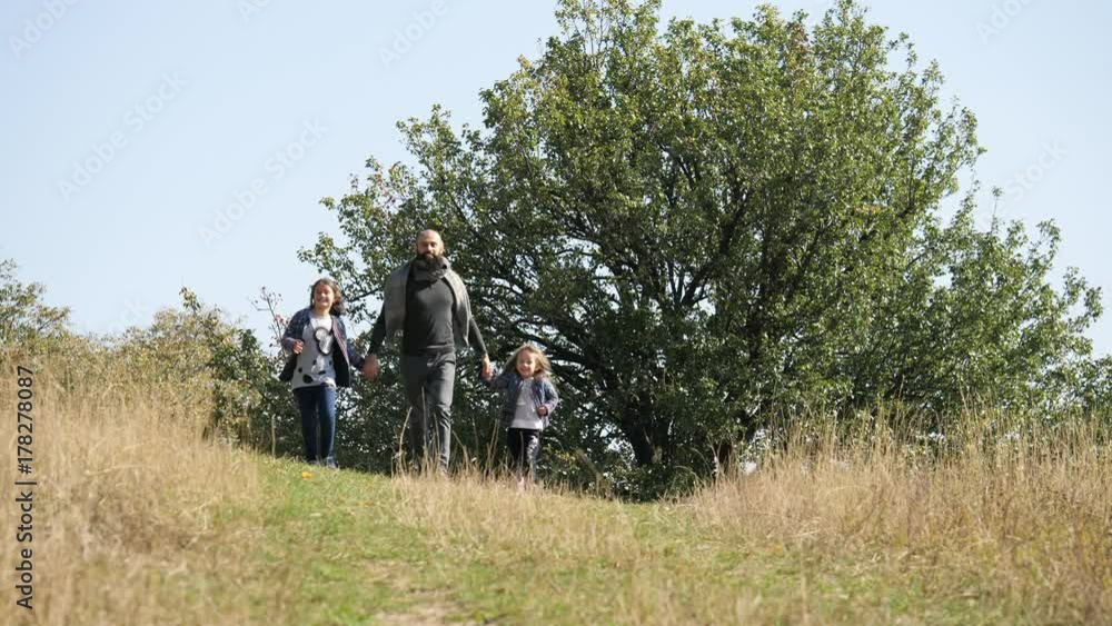 Father with his two daughters running from the hill at camera. Father with his two daughters running from the hill at camera.