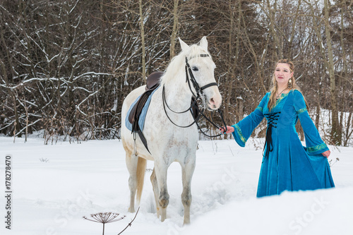 Woman in national dress and white horse in a winter forest