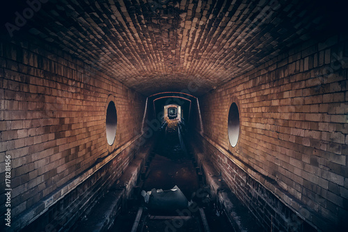 Foto Red brick underground sewer tunnel with dramatic mysterious atmosphere