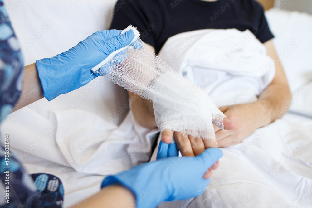 the nurse puts a bandage on a hand to a sick patient at home the nurse puts a bandage on a hand to a sick patient at home