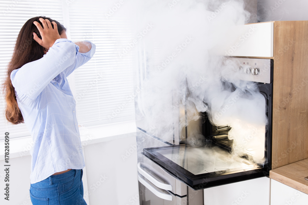 Shocked Woman Looking At Smoke Coming From Oven StockFoto Adobe Stock