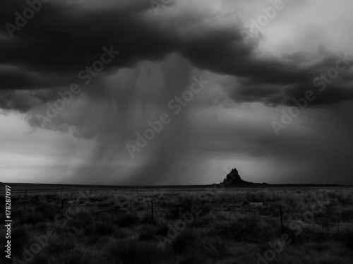 Dramatic Monsoon Clouds and Rain Bands Over Silhouette of Mountain in Desert