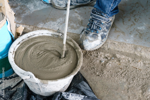 Obraz na plátne Mixing cement with a mixer in a bucket on the street