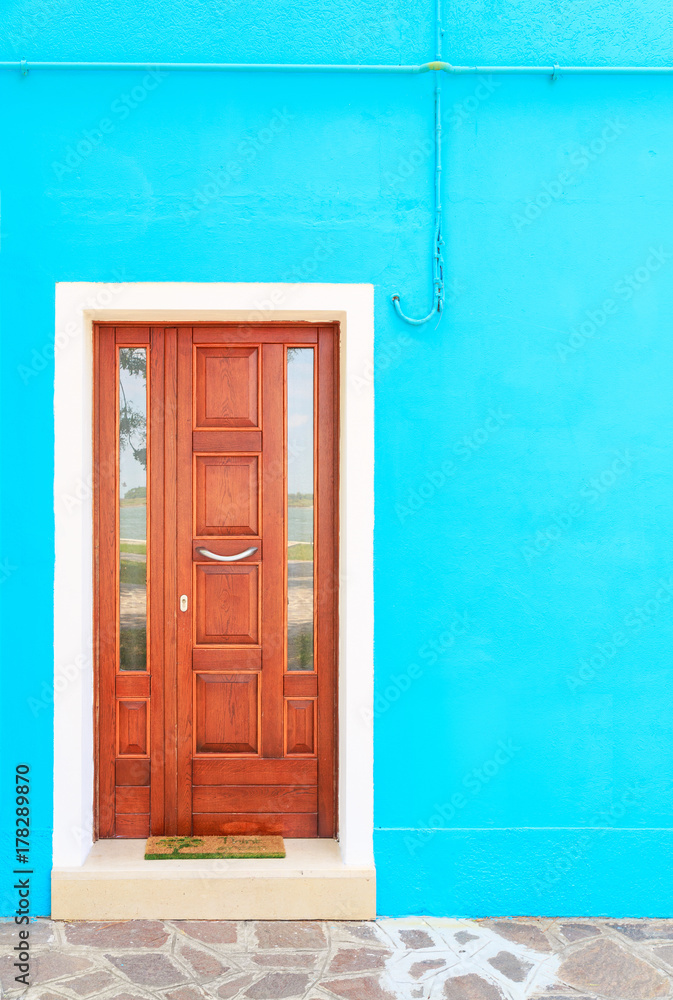 Fototapeta premium Brown door on blue wall of houses on the famous island Burano, Venice, Italy