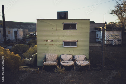 Three ratty chairs in front of an abandoned trailer