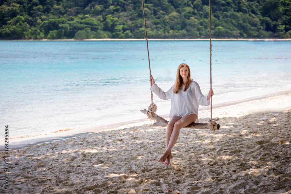 Girl sitting on the swing on the tropical beach