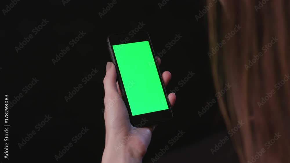 Young Woman is Holding Phone with green Screen at studio with black Bbackground, tap Young Woman is Holding Phone with green Screen at studio with black Bbackground, tap