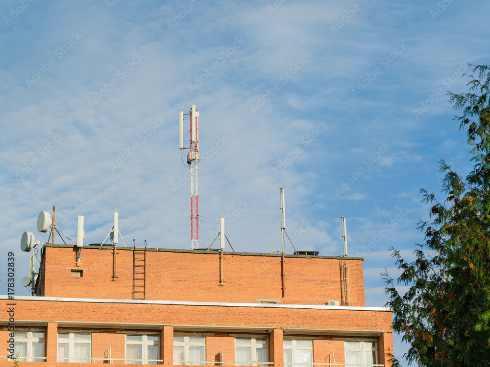 Antennas mounted on the roof of a residential brick house.