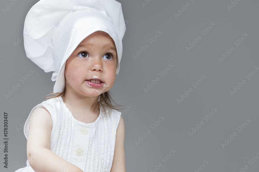 Portrait of Caucasian Little Girl in Cook Uniform Posing with Smudgy Face Against Gray Background Portrait of Caucasian Little Girl in Cook Uniform Posing with Smudgy Face Against Gray Background