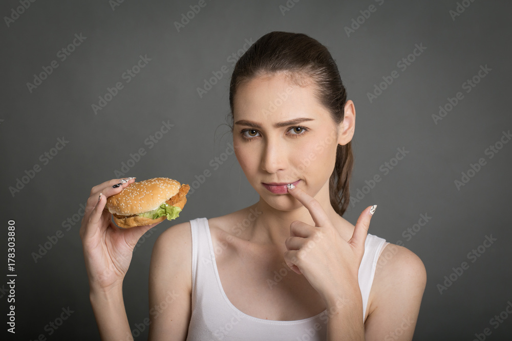 A woman looking to a burger isolated on gray balckgroung A woman looking to a burger isolated on gray balckgroung