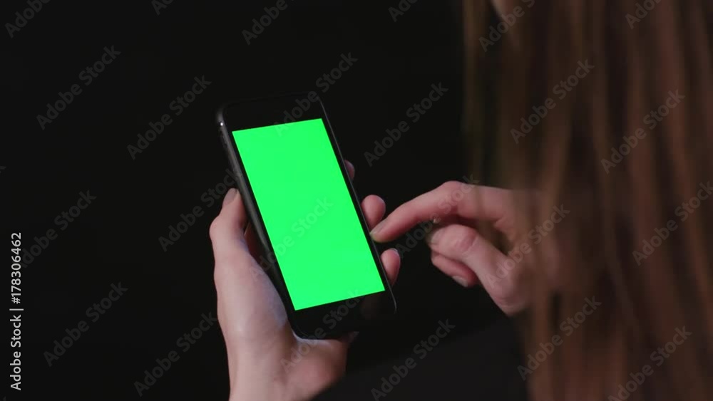 Young Woman is Holding Phone with green Screen at studio with black Bbackground, scroll up Young Woman is Holding Phone with green Screen at studio with black Bbackground, scroll up