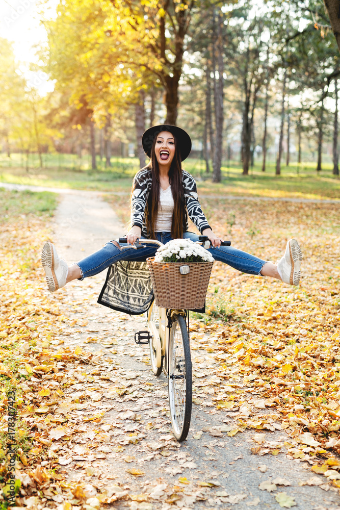 Happy woman riding bike bicycle in fall autumn park