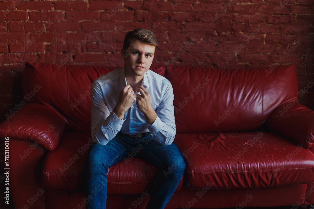 the guy in jeans and shirt sitting on the couch the guy in jeans and shirt sitting on the couch
