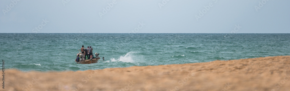 The blurred image of fishermen on the fishing boat in the sea near the shore