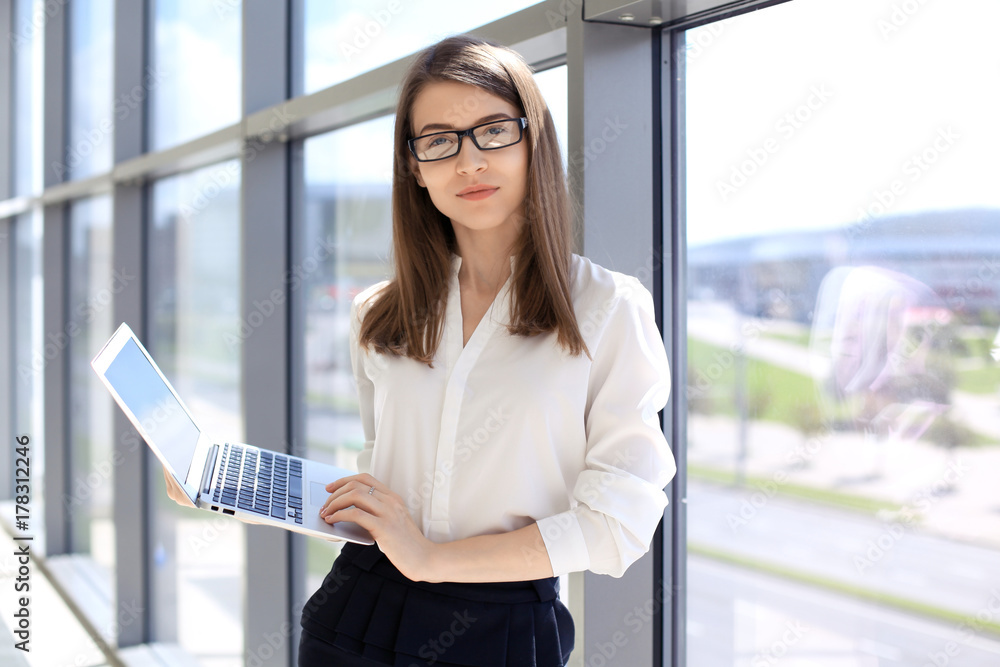 Fototapeta premium Modern business woman typing on laptop computer while standing in the office before meeting or presentation