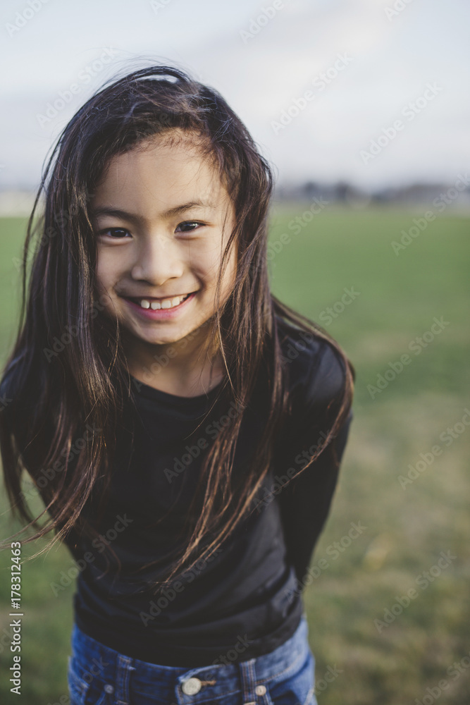Cute elementary school aged asian girl happy in windy field Cute elementary school aged asian girl happy in windy field