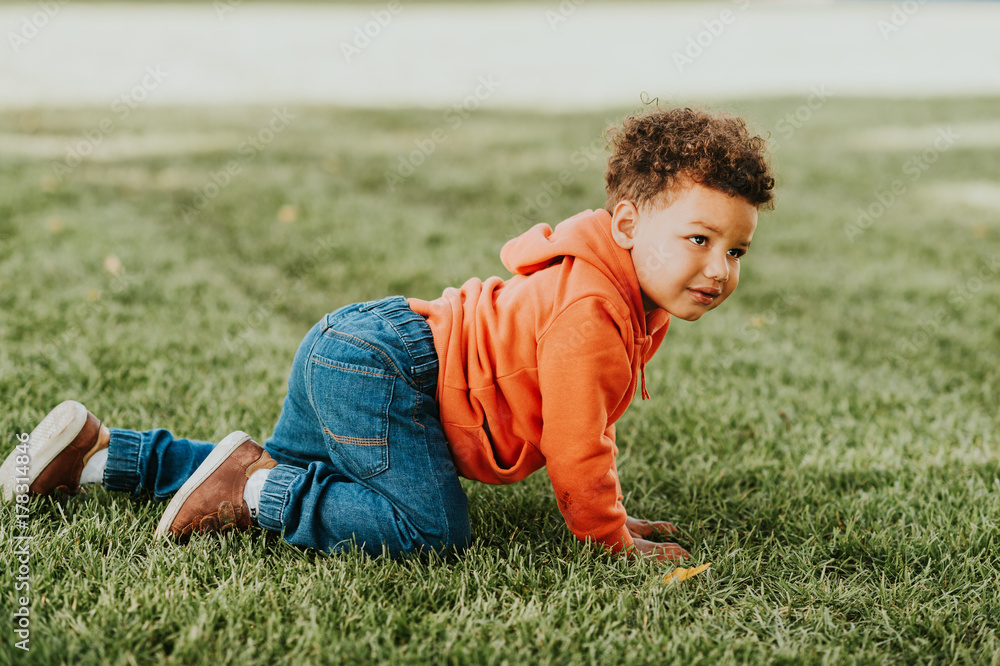 Adorable funny toddler playing outside, baby boy enjoying nice sunny day, 1-2 year old african kid crawling on the grass, film look toned image Adorable funny toddler playing outside, baby boy enjoying nice sunny day, 1-2 year old african kid crawling on the grass, film look toned image