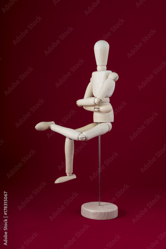 a wooden mannequin in sitting position with a red background a wooden mannequin in sitting position with a red background