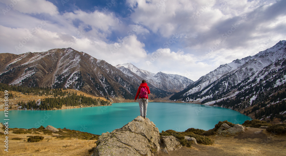 a girl stands on a mountain, a mountain lake