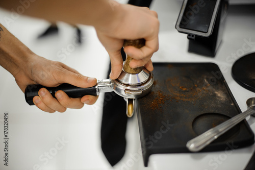 Barista making a coffee tablet with help of temper
