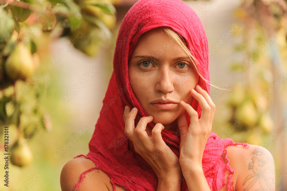 Beautiful young girl trying on a red scarf. Autumn time for harvest. Orchard. The concept of harvesting. Beautiful young girl trying on a red scarf. Autumn time for harvest. Orchard. The concept of harvesting.