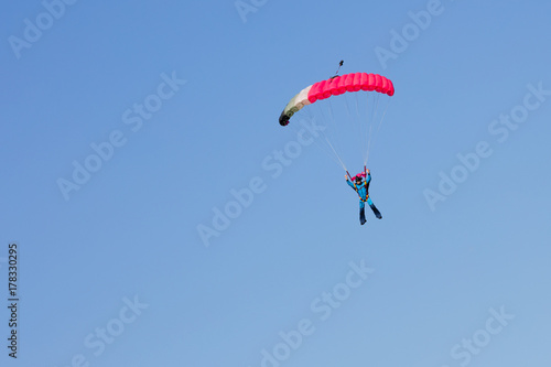 skydiver on black and pink parachute on background clear blue sky