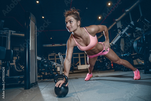 Fototapeta Naklejka Na Ścianę i Meble -  Sexy athletic young girl training legs in gym
