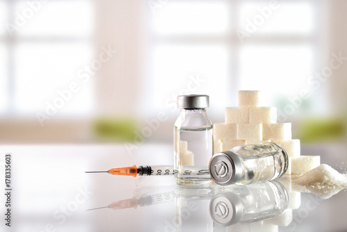 Insulin vials and syringe on white table with background windows