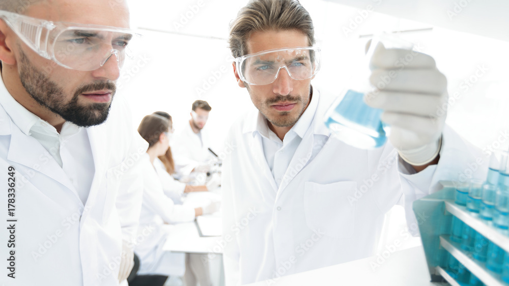 closeup. scientist and assistant studying the solution in the glass tube closeup. scientist and assistant studying the solution in the glass tube