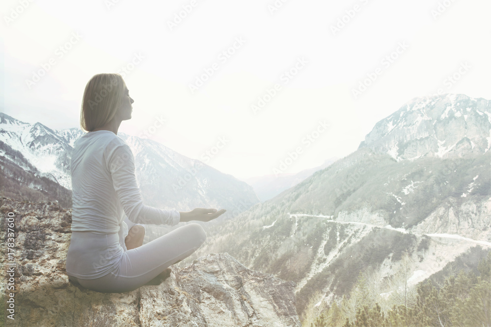 woman doing yoga exercises over the top of a mountain