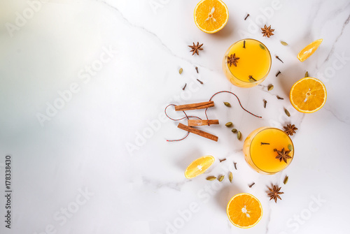 Fall, winter cocktails, Hot and spicy winter orange punch with cinnamon, anise stars, cardamom, cloves. On a white marble table, with ingredients, in glasses. Copy space top view