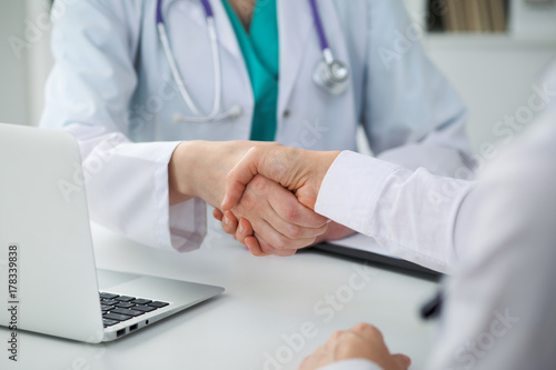 Doctor and patient shaking hands, close-up.  Physician talking about medical examination results. Medicine, healthcare and trust concept